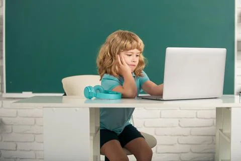 Kid boy learning lesson at school, making homework and using notebook gadget Stock Photos