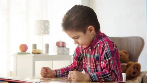 Kid boy look and examine book with color pictures with interest and fantasy Stock Footage 78201197