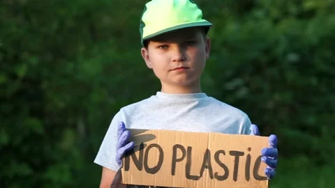 Kid boy with No Plastic carton poster looking to camera in gloves holding gar Stock Footage 134633112