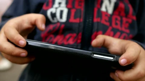 Kid boy play game on a mobile smartphone touchscreen outdoors in park Stock Footage 50548219