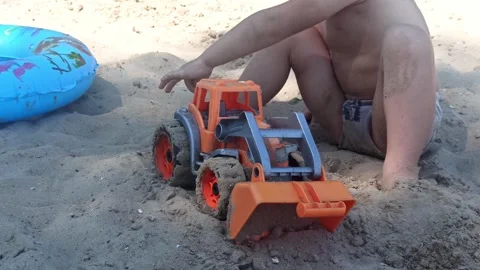 Kid boy plays with a car toy in sand, summer holidays at the seaside.4k Stock Footage 249694677