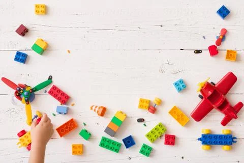 The kid boy plays in multi-colored cubes on a white wooden table. Top view Stock Photos