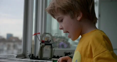 Kid Boy Plays With Toy Constructor Building on Windowsill Near Window. City Life Vídeos de archivo 277800488