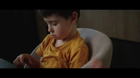 Kid boy sitting around a table and playing with kinetic sand at home. High Video stock 269347874