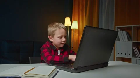 Kid boy is studing at home typing on laptop then looking at camera and showes Stock Footage 171160634