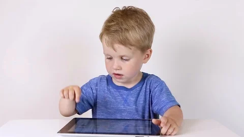 Kid boy using touchscreen tablet technology for playing video Stock Footage 93445052