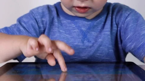 Kid boy using touchscreen tablet technology for playing video Stock Footage 93445723