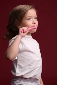 Kid brushing her teeth. Close up. Red background Stock Photos