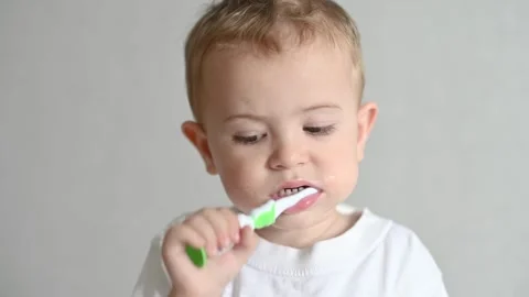 The kid is brushing his teeth with a toothbrush on a gray background. Oral Stock-Footage 244923537