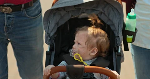 Kid is capricious in the stroller, sucking a pacifier in his mouth. Small child Stock Footage 137424233