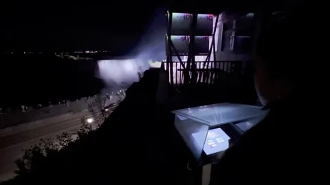 Kid changes niagara falls color illumination at night Stock Footage 302546488