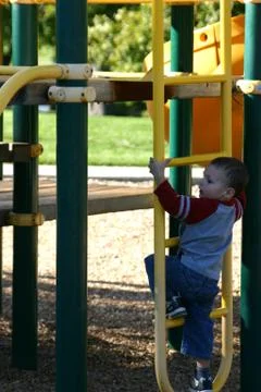 Kid climbing up the slider Stock Photos