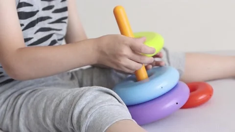 The kid collects a developing pyramid of colorful. The child puts the toy rings Stock Footage 157128348