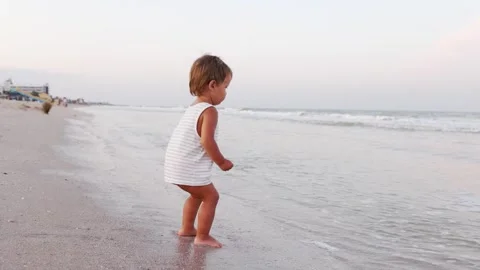 Kid collects shells and pebbles in the sea on a sandy bottom under the summer Stock Footage 348403160