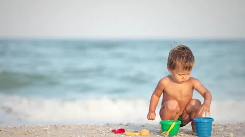 Kid collects shells and pebbles in the sea on a sandy bottom under the summer Stock Footage 348403560