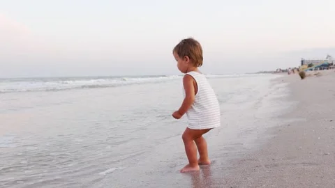 Kid collects shells and pebbles in the sea on a sandy bottom under the summer Stock Footage 348686223