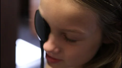 Kid covering eye to take eye exam Stock Footage 302244620