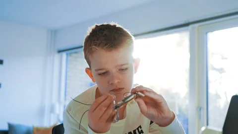 Kid creates a robot and tries to make a circuit board fit into his design Stock Footage 102179605