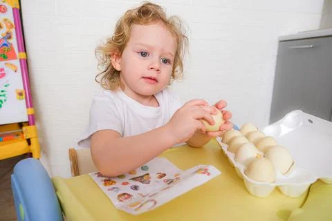 Kid decorating Easter egg with sticker on table. Child prepares for Christian Stock Photos