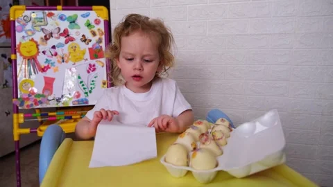 Kid decorating easter eggs with stickers at home. Preschooler child playing with Stock-Footage 330108945