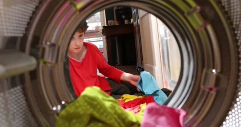 Kid is doing laundry in washing machine at home. View looking out from Inside Stock Footage 152857485