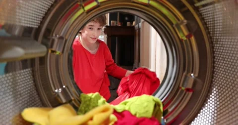 Kid is doing laundry in washing machine at home. View looking out from Inside Stock Footage 152857566