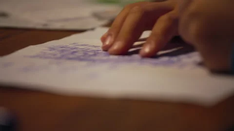 A kid doing school homewok and writing text on paper over a wooden table Stock Footage