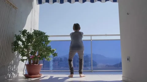 Kid doing sport exercises, crouching on the balcony. Sport, healhty lifestyle Stock Footage 134467482
