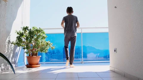 Kid doing sport exercises, running, jogging on balcony. Active leisure at home Stock Footage 128942191
