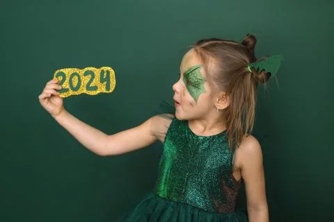 Kid with a drawing on face in shape of dragon looks at numbers of 2024 new ye Stock Photos