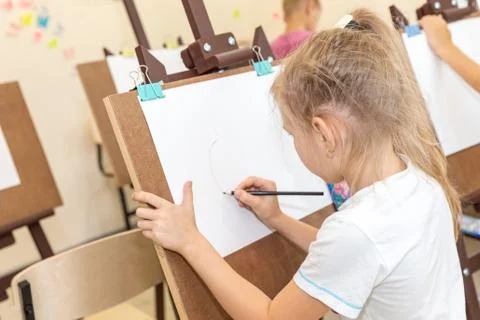 Kid drawing image on easel in classroom Stock Photos
