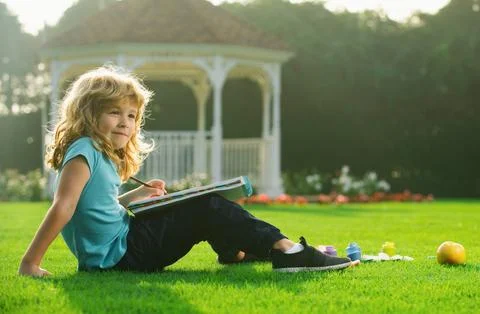 Kid draws in park having fun on nature background. Children creative, developing Stock Photos