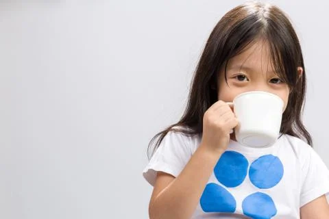 Kid drinking milk on studio isolated white background. Stock Photos