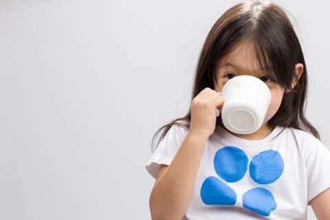 Kid drinking milk on studio isolated white background. Stock Photos