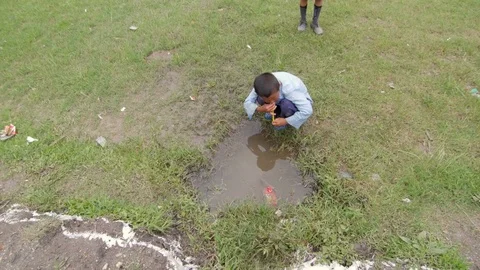 Kid drinking polluted water from a puddle in Nepali countryside Stock Footage 75887841