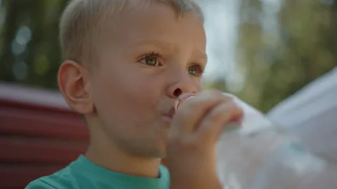 Kid drinking water outside.  Close-up portrait of a little boy drinking water Stock-Footage 343208499