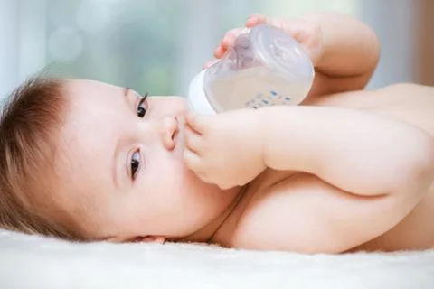 Kid drinks compote from a bottle at home Stock Photos
