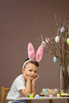 Kid dyeing Easter eggs. Child in bunny ears dye colorful egg for Easter hunt 写真素材