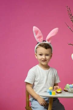 Kid dyeing Easter eggs. Children in bunny ears dye colorful egg for Easter hunt Foto stock