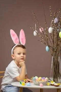 Kid dyeing Easter eggs. Children in bunny ears dye colorful egg for Easter hunt Foto stock