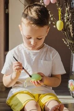 Kid dying Easter eggs. Boy dye colorful egg for Easter hunt. Home decoration for Stock Photos