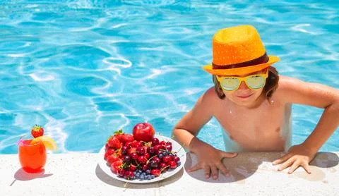 Kid eating fresh fruits on watter pool. Child in swimming pool playing in summer Stock Photos