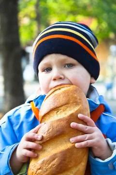 The kid eats bread during autumn walk in the park Stock Photos