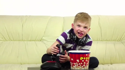 Kid eats popcorn and plays joystick online game, slow motion Stock Footage 75926929