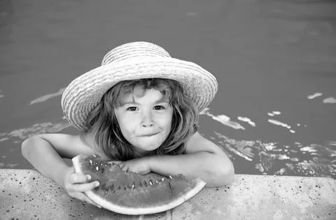 Kid eats watermelon in the pool. Cute boy eating slice of red watermelon on the Stock Photos