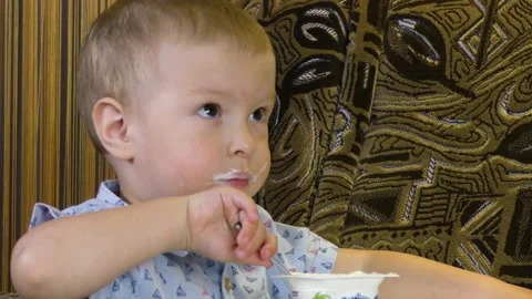 The kid eats yogurt on his own Stock Footage 132506137
