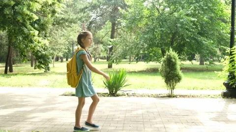 Kid elementary school student walks through the park to school in the morning 库存影片 200323197