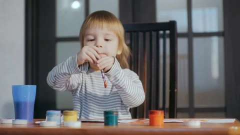The kid is engaged in drawing with a brush using gouache paints. Stock Footage 151736371