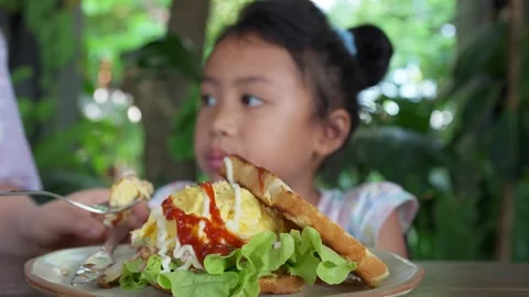 Kid enjoy eating scrambled eggs and vegetable on wooden table. Stockbeeldmateriaal 246464277