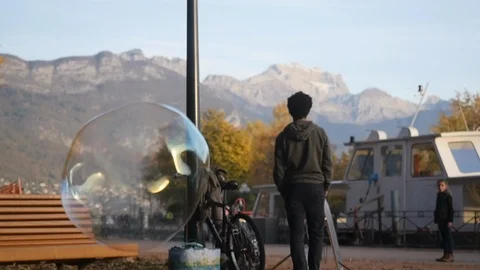 Kid exploding bubble in the park with moutain in the background slow motion Stock Footage 87693997